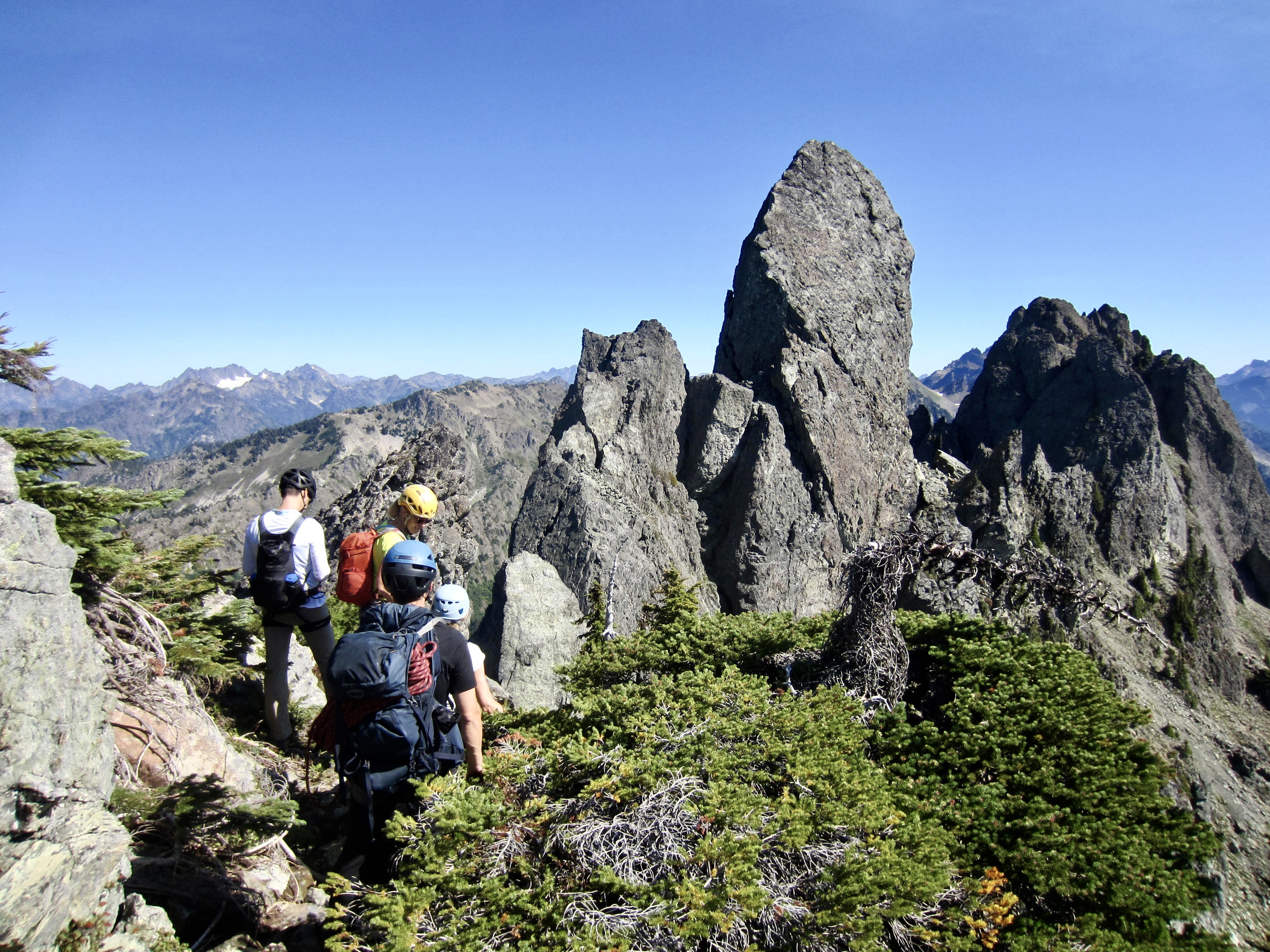 Four climbers scramble toward the summit pinnacle on Mt. Cruiser in the Olympic Mountains, WA.