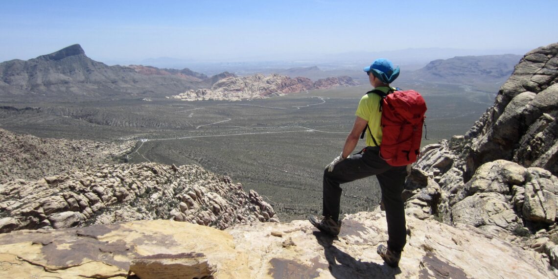 A hiker looks out over Red Rock Basin from the north ridge of White Rock Peak