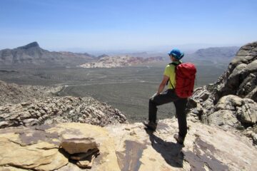 A hiker looks out over Red Rock Basin from the north ridge of White Rock Peak
