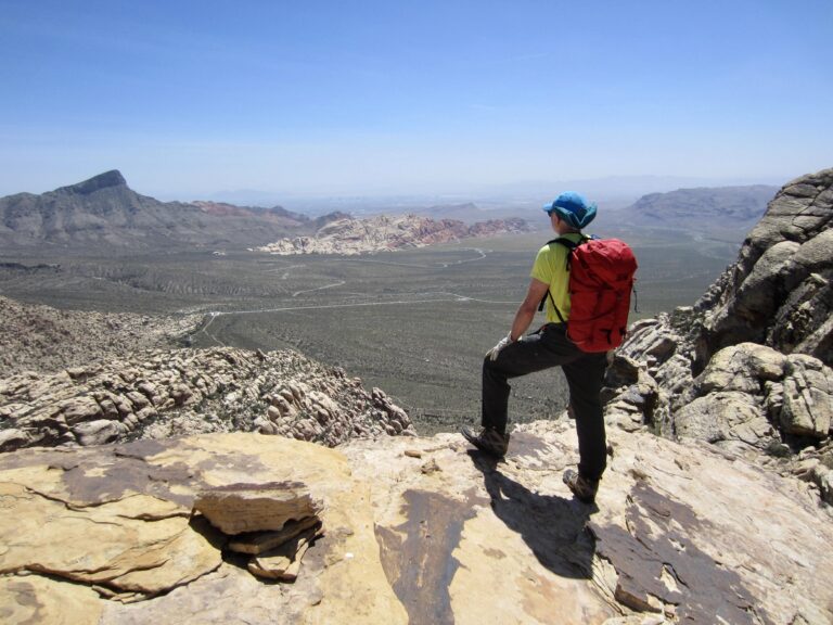 A hiker looks out over Red Rock Basin from the north ridge of White Rock Peak