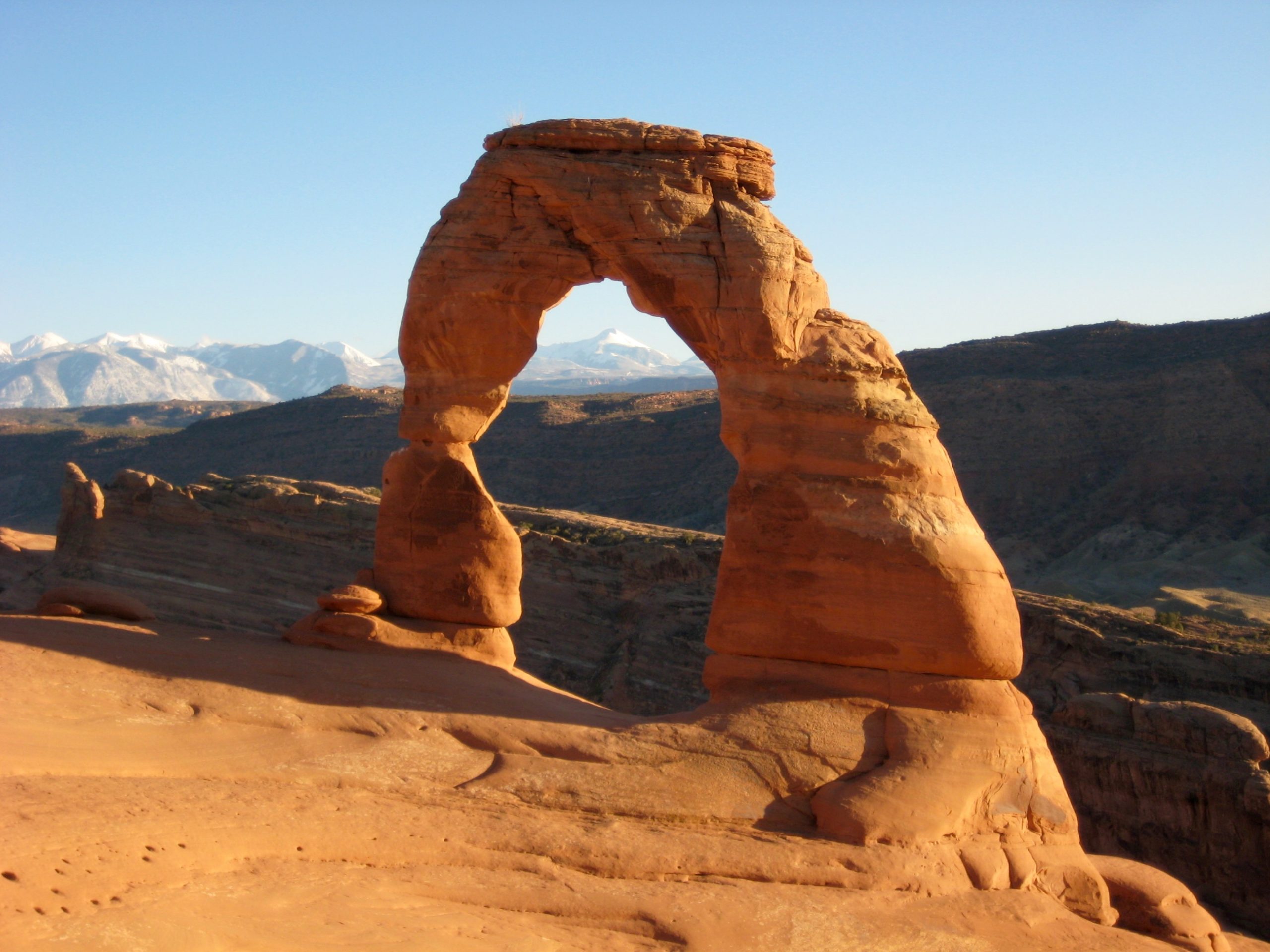 Setting sunlight casts a warm glow on the orange sandstone of Delicate Arch in Arches National Park