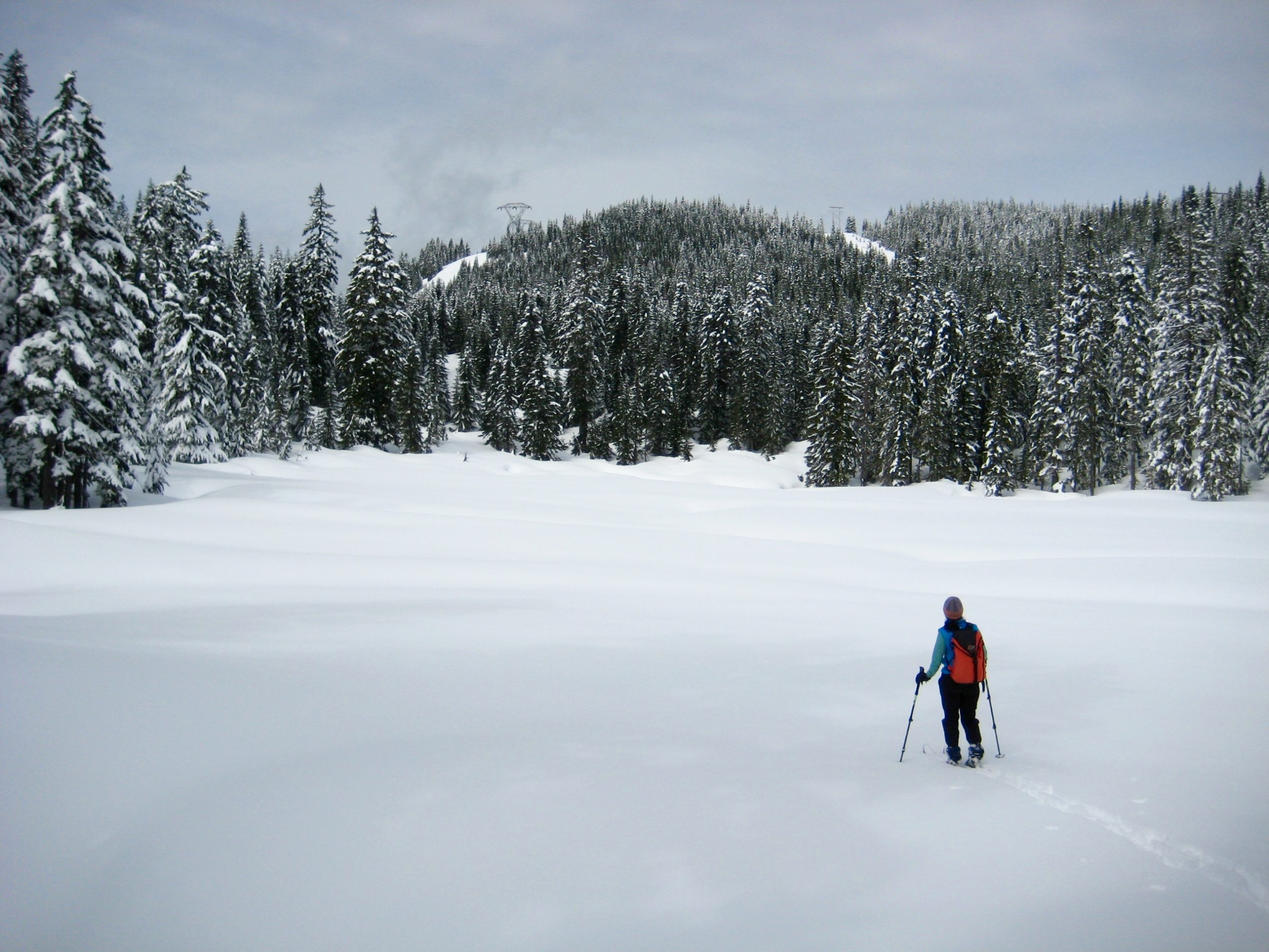 A backcountry skier stands at the edge of snow-covered Hyak Lake during the Nordic Pass Loop near Snoqualmie Pass, Washington