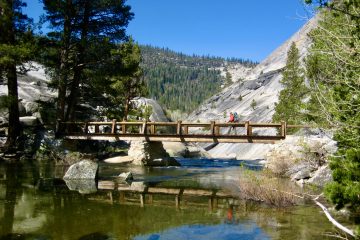 A backpacker crosses a bridge over the Merced River in Upper Merced Canyon of Yosemite National Park
